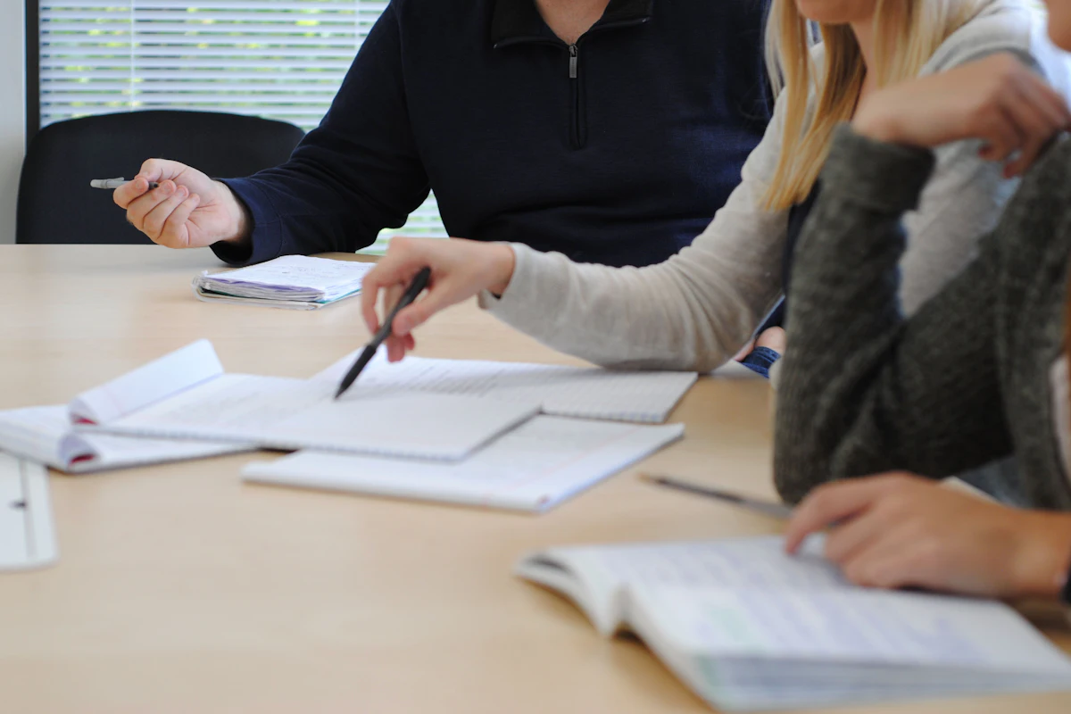 Colleagues review notes together at a table during a meeting