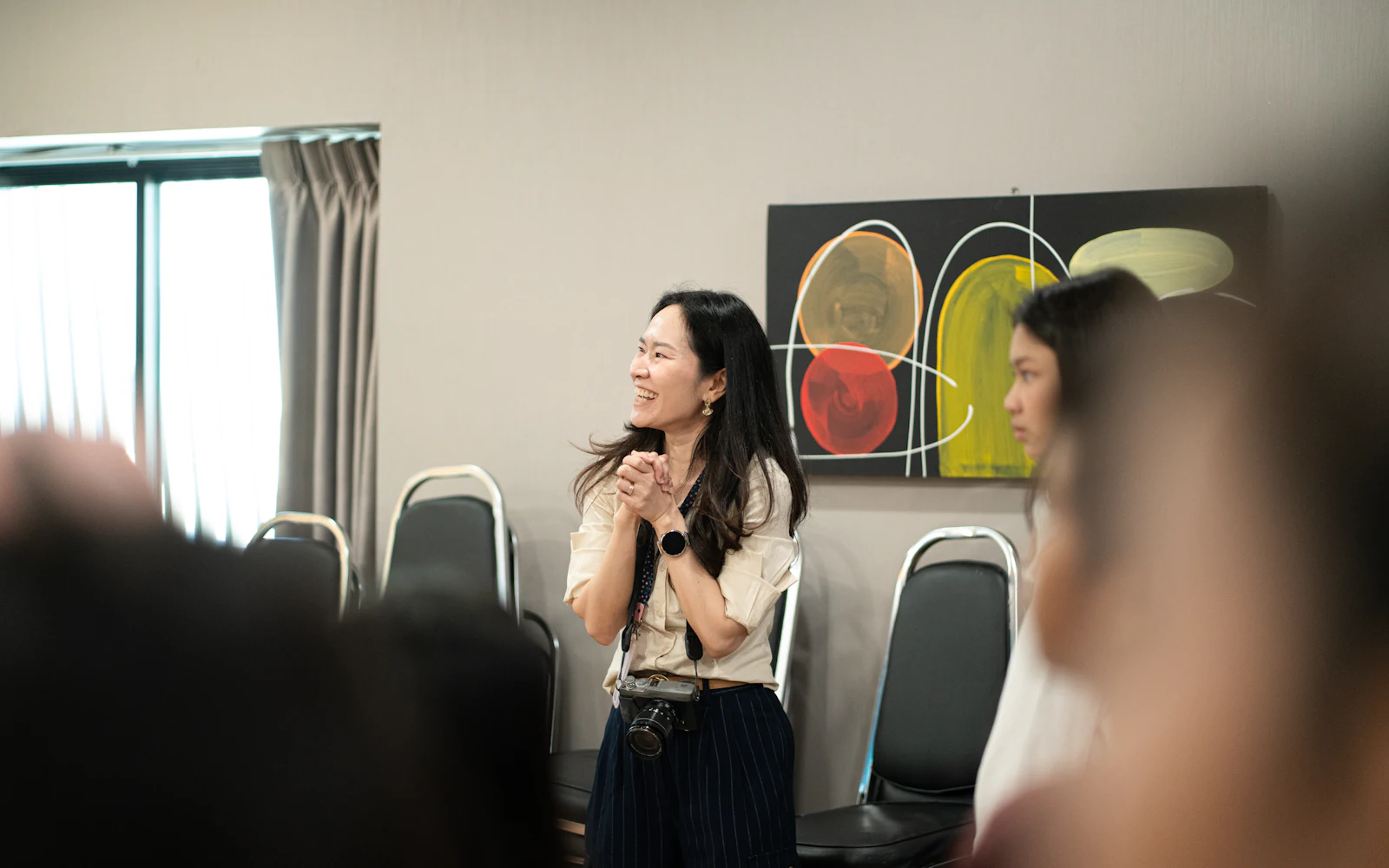A smiling facilitator speaks with her hands while leading a small group session